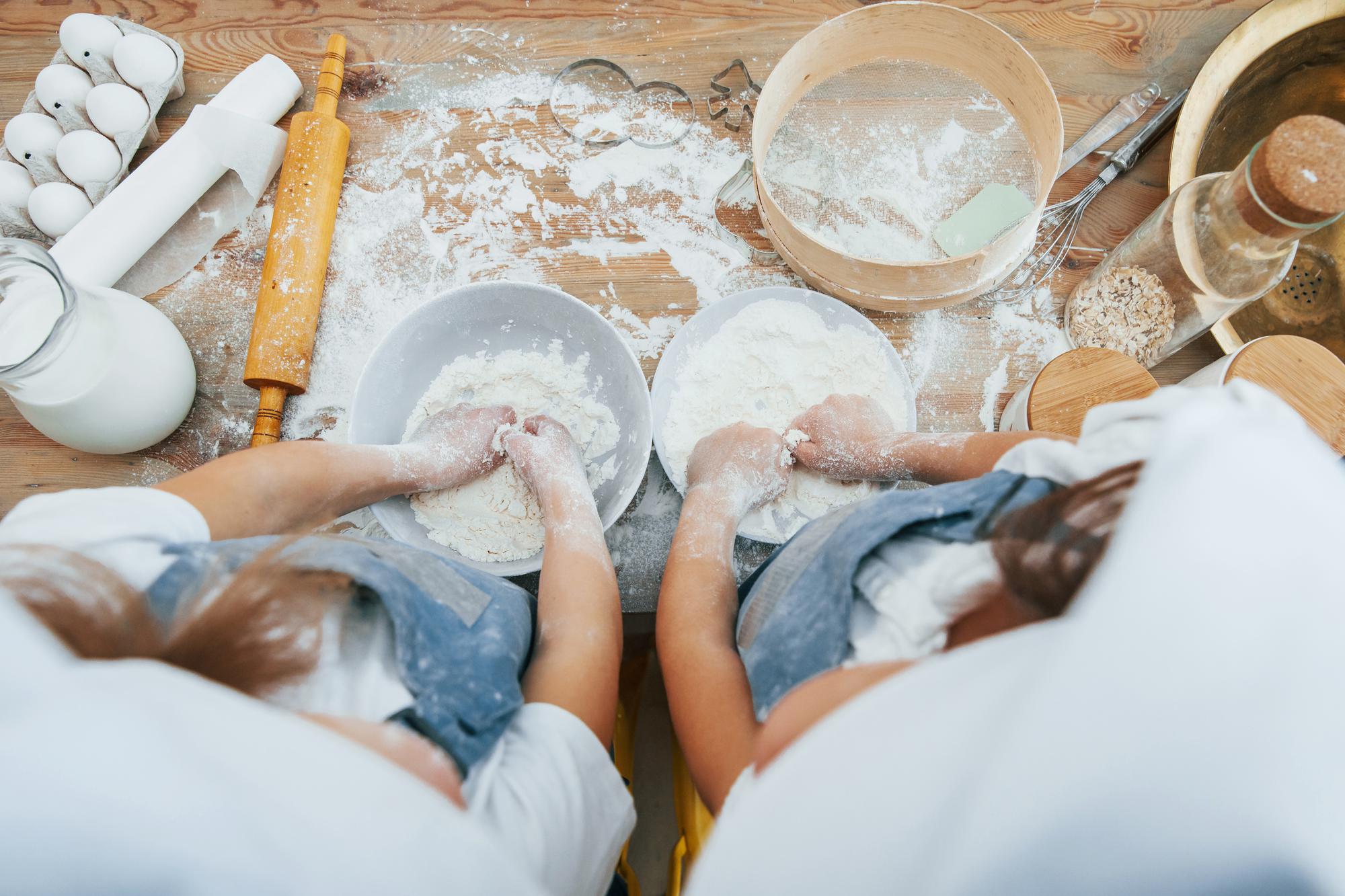 Student kneading dough on wooden table